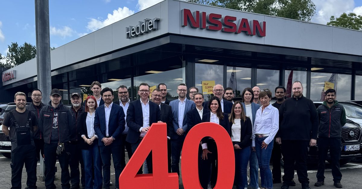 Team der Heddier Gruppe vor dem Autohaus in Haltern mit rotem 40-Jahre-Motiv